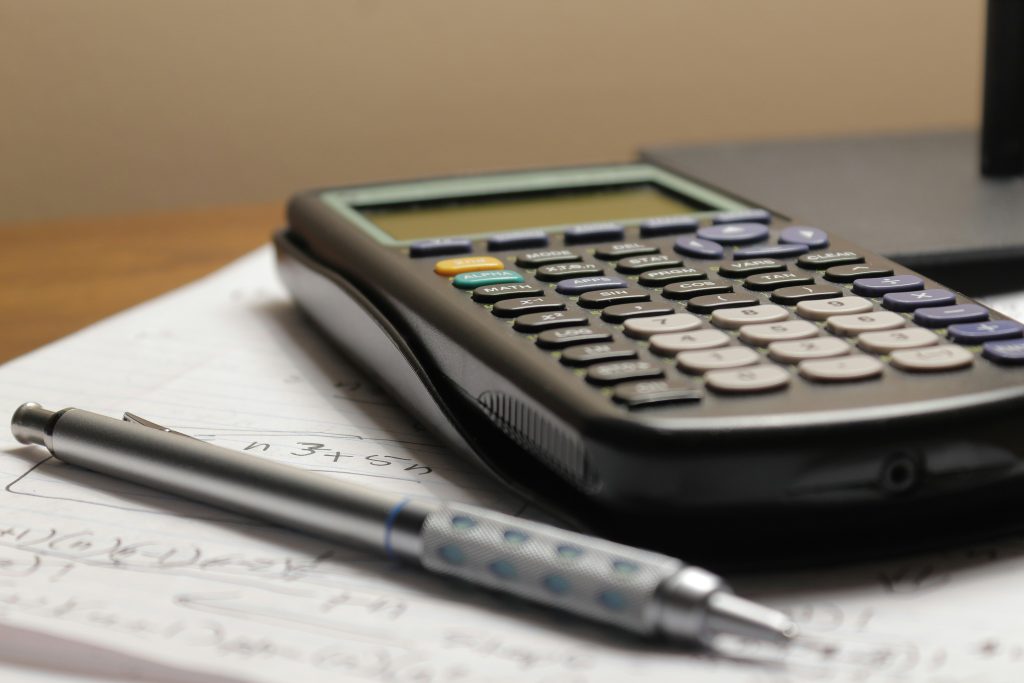 Calculatrice et crayon posés sur des calculs, estimation et devis de travaux de peinture Delphine Rénove
